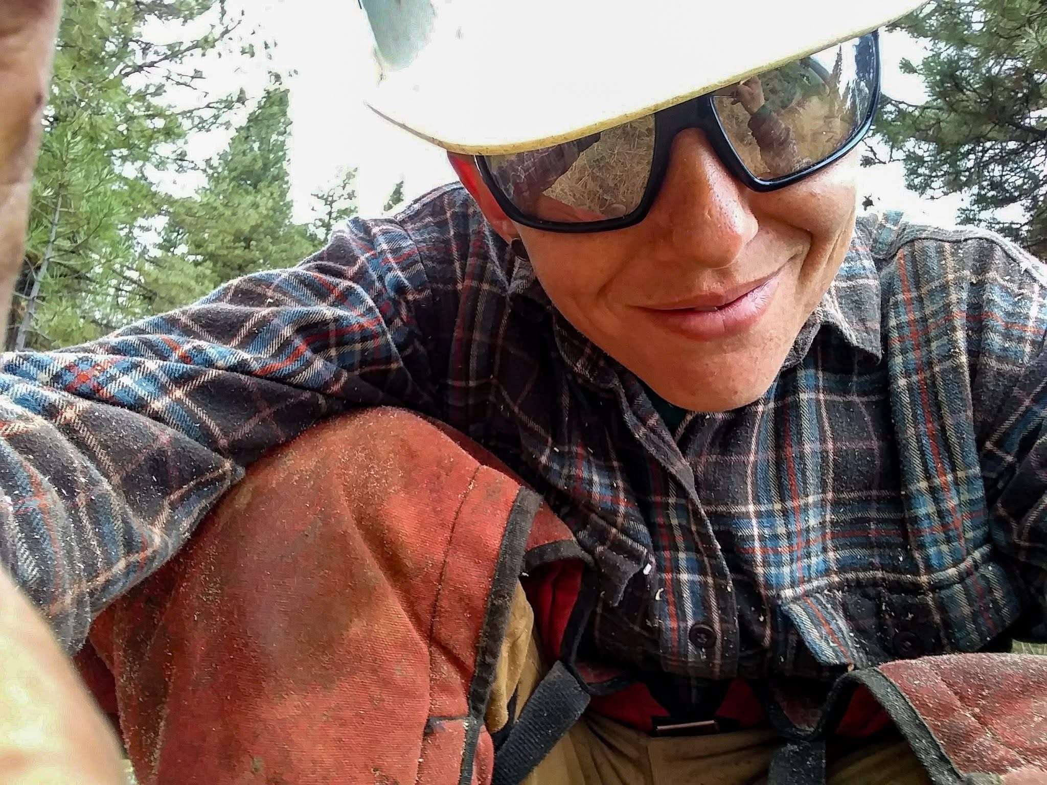 Photo of Aiden in chainsaw chaps in the woods.